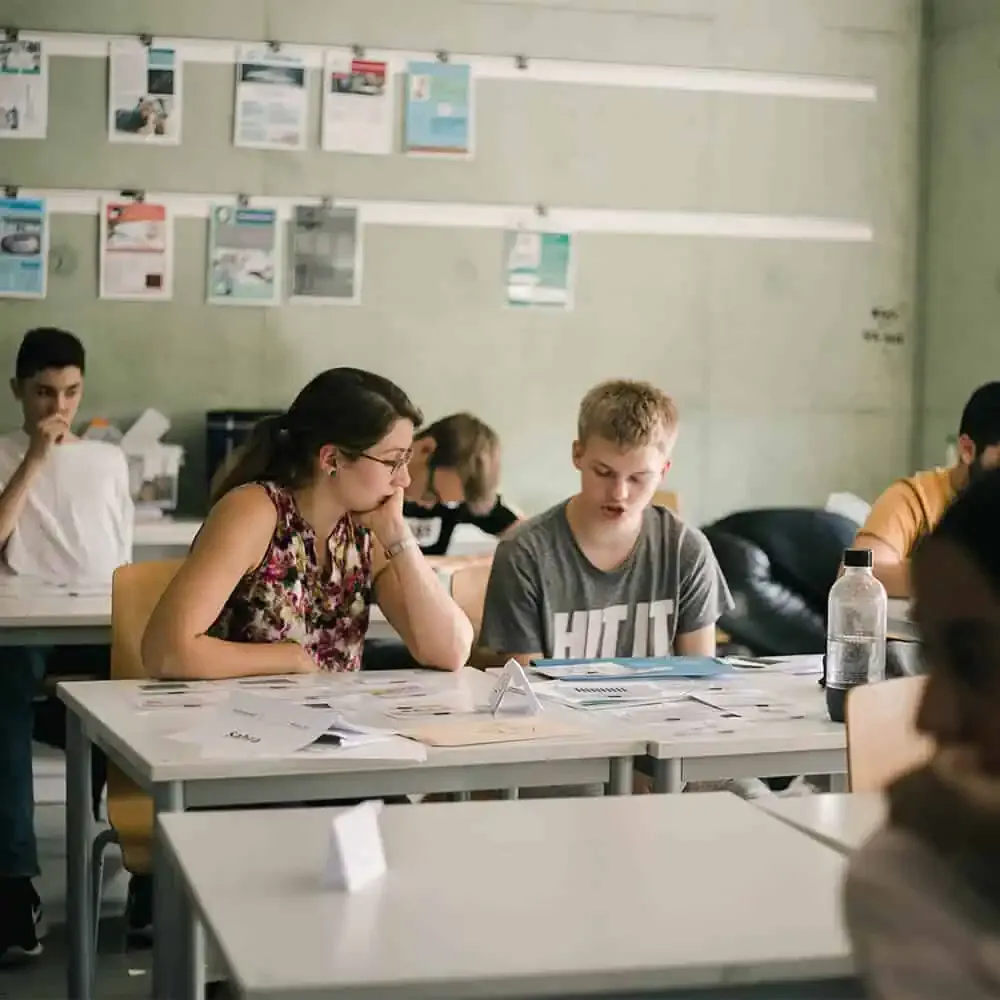 Schülerinnen und Schüler arbeiten gemeinsam an Gruppentischen