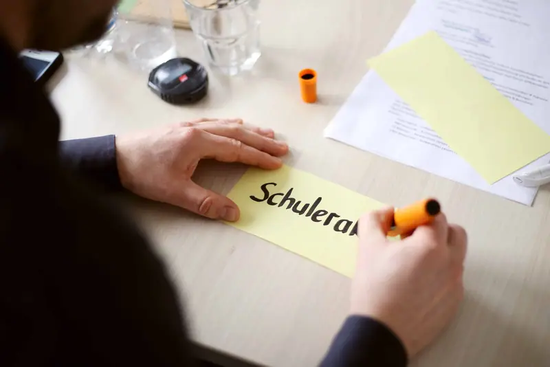 Hände notieren Maßnahmen auf Moderationskarten während einer Planungssitzung